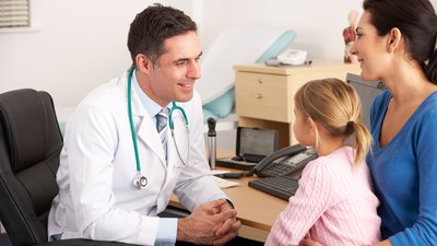 American doctor talking to young child and mother