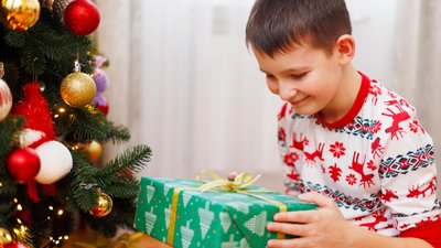 Boy holding Christmas gift near tree