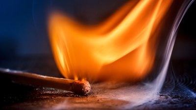 Burning match with a flame of fire and smoke on a black background