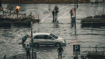 Car in flooded street with people pushing it