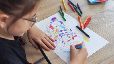 Child draws fractal patterns with crayons as part of art therapy
