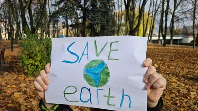 Child holding hand drawn save the earth paper