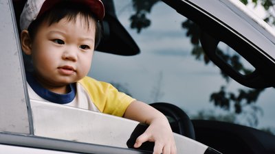 Child with Baseball Cap Leans Out of Car Window