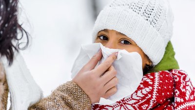 Cropped view of mother wiping with napkin nose of cute daughter in winter park