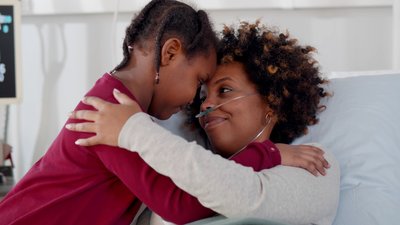 Cute african daughter visiting sick mother in hospital and hugging
