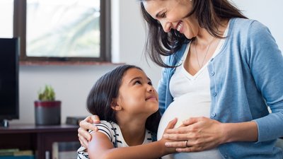 Daughter touching the belly of her pregnant mother