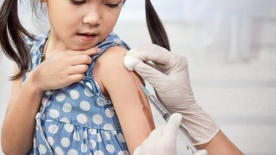 Doctor injecting vaccination in arm of asian little child girl