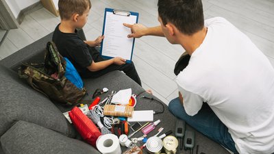 Father and son assemble the emergency evacuation bag together and put necessary items into backpacks