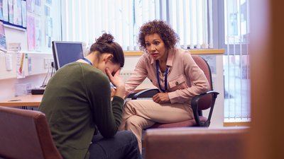 Female College Student Meeting With Campus Counselor Discussing Mental Health Issues