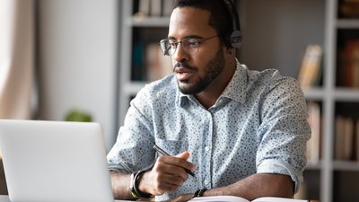 Focused african businessman wear headphones study online watching webinar