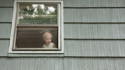 Girl looking through house window