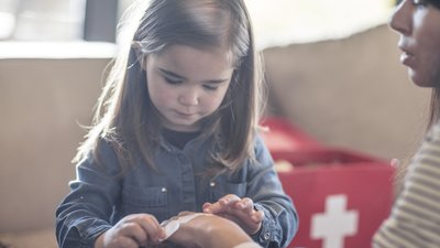 Girl putting bandaid on mother's hand