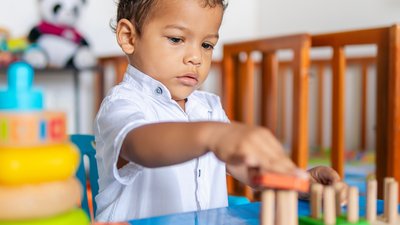 Latino 2-year-old boy plays with educational toys at home