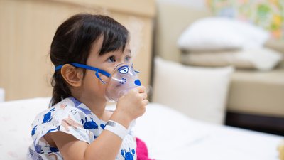 Little asian girl sick making inhalation with nebulizer to reduce coughing and sputum in the neck