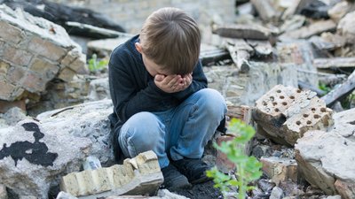 Little boy near the destroyed house