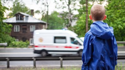 Little boy watching for ambulance car is passing on the road
