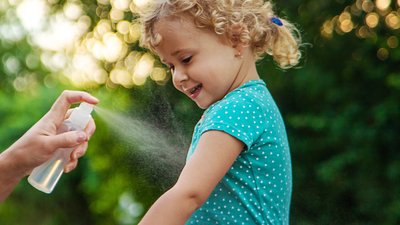 Mom sprays her child with mosquito repellent