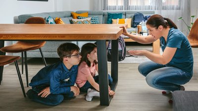 Mother explaining to her children how to protect themselves in an earthquake by getting under the table