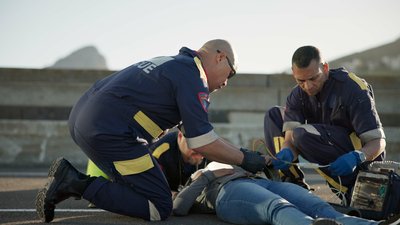 Paramedic, rescue and team with patient, outdoor and EKG to check heart