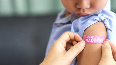 Portrait of happy smile vaccinated little asian kid boy children ages 5 to 11 years old posing show arm with medical plaster after Injection vaccine