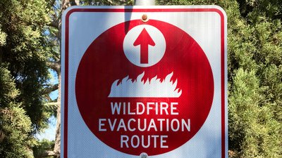 Red wildfire evacuation route sign with ahead arrow that point in the correct direction of voluntary or mandatory egress during fire emergency