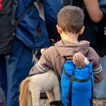 Refugee boy with toys and backpack