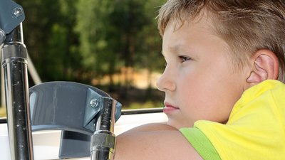 Seven years old boy with crutches sadly looks out of the window