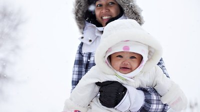 Smiling baby in the snow with mom