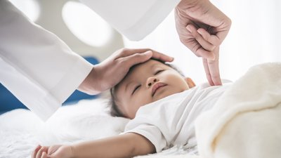 The doctor is using two fingers to press down in the middle of the baby's chest