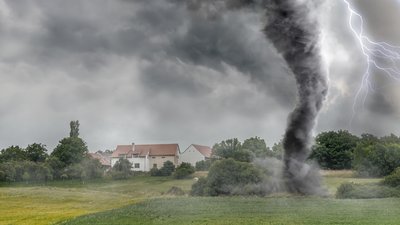 Tornado on the ground near houses with lightning in the sky