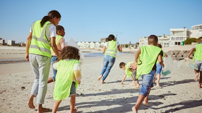 Woman and group of children cleaning beach