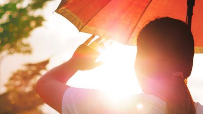 girl holding an umbrella and raising her hand to block the hot sunlight